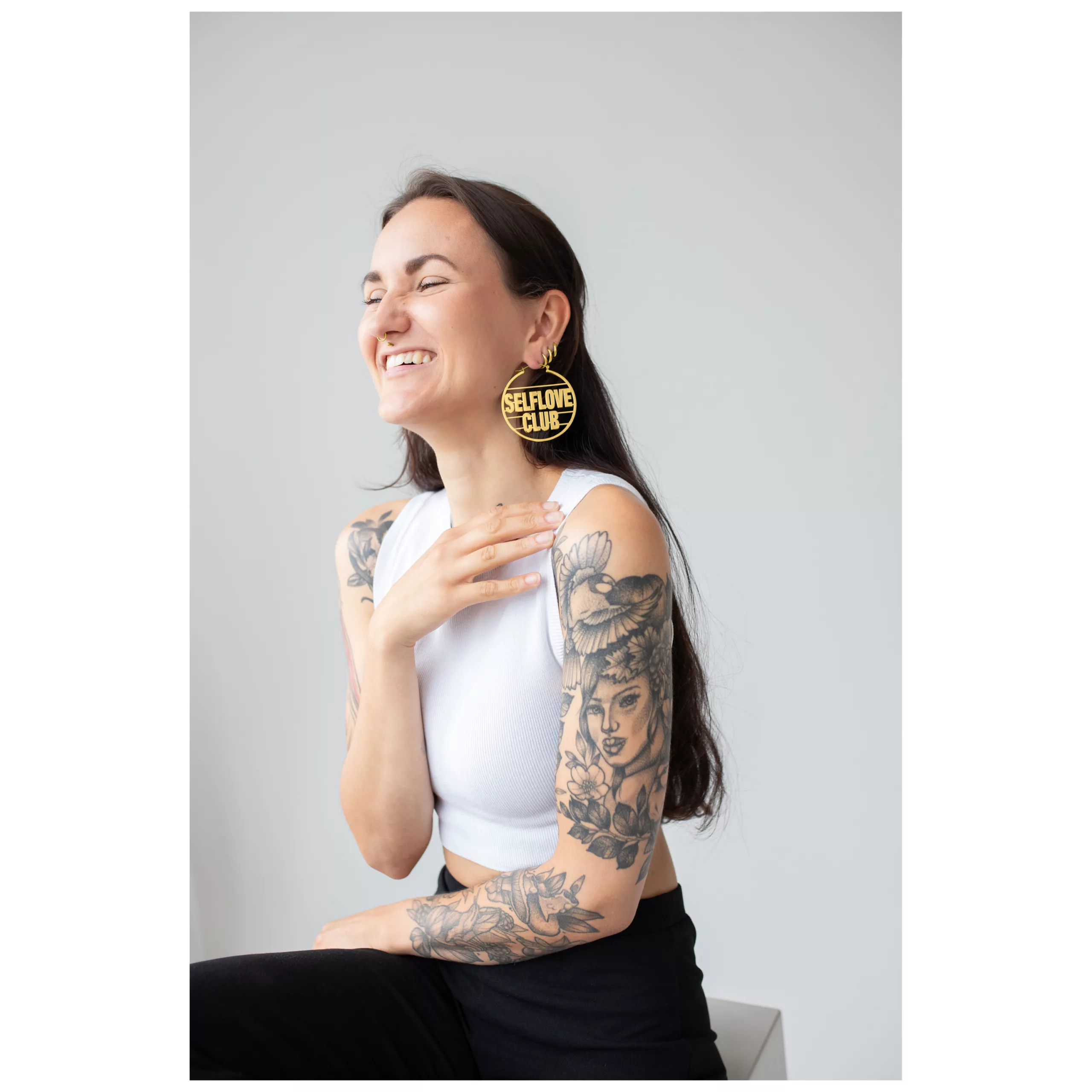 Orecchini a cerchio Selflove Club dorati Donna sorridente con orecchini a cerchio Selflove Club dorati su sfondo neutro