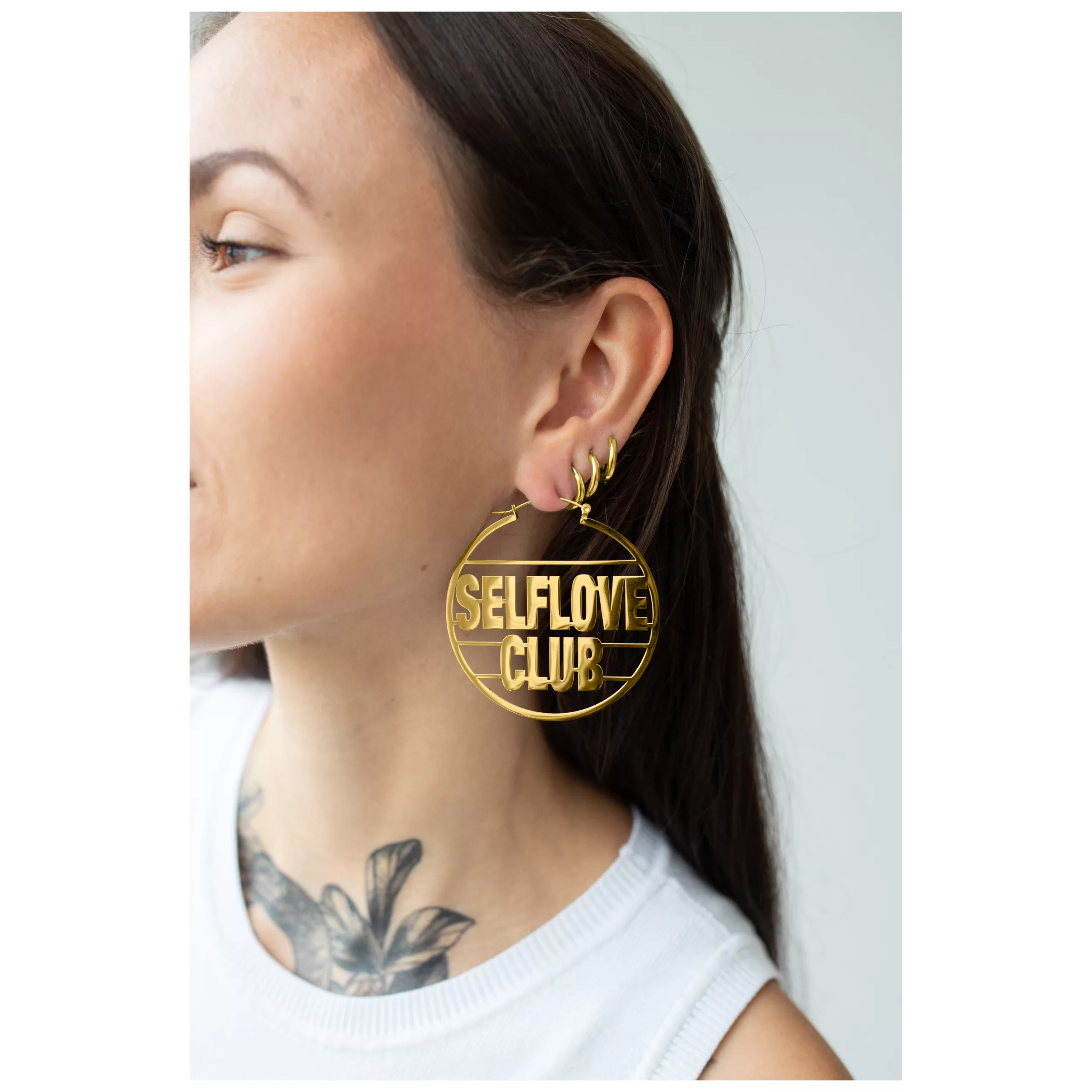 Orecchini Gold Selflove Club all'orecchio Donna indossa grandi orecchini d'oro con scritta 'Selflove Club'