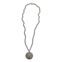 Collana dorata con ciondolo a forma di moneta con teschio su sfondo bianco