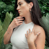 Donna indossa orecchini in metallo nero con piastrine su sfondo verde