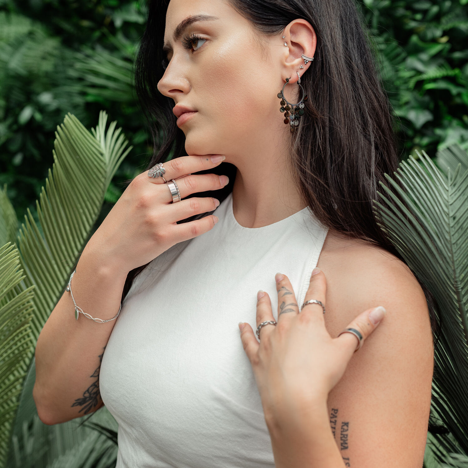 Donna indossa orecchini in metallo nero con piastrine su sfondo verde