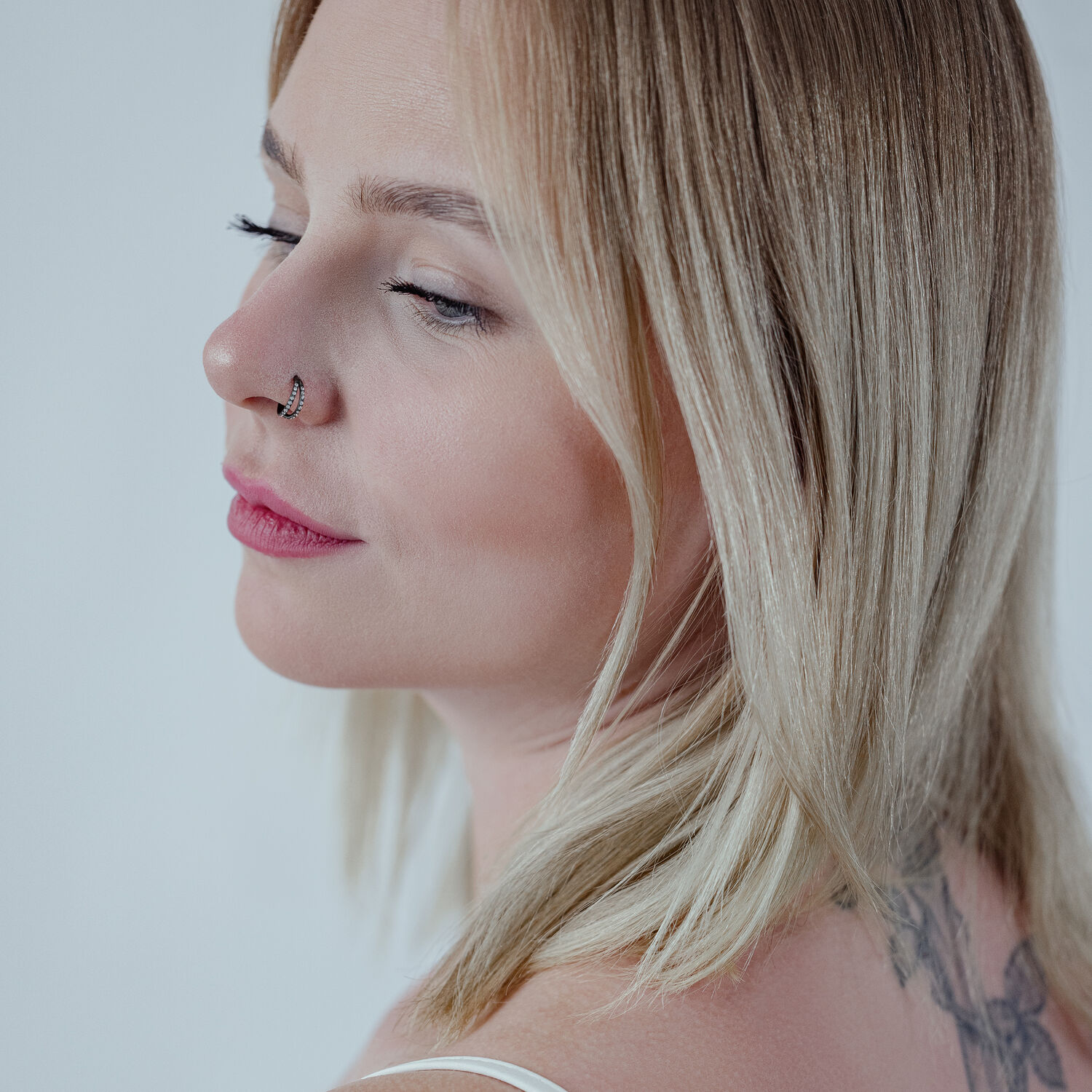 Donna con capelli biondi indossa un clicker con cristallo nero nel piercing al naso