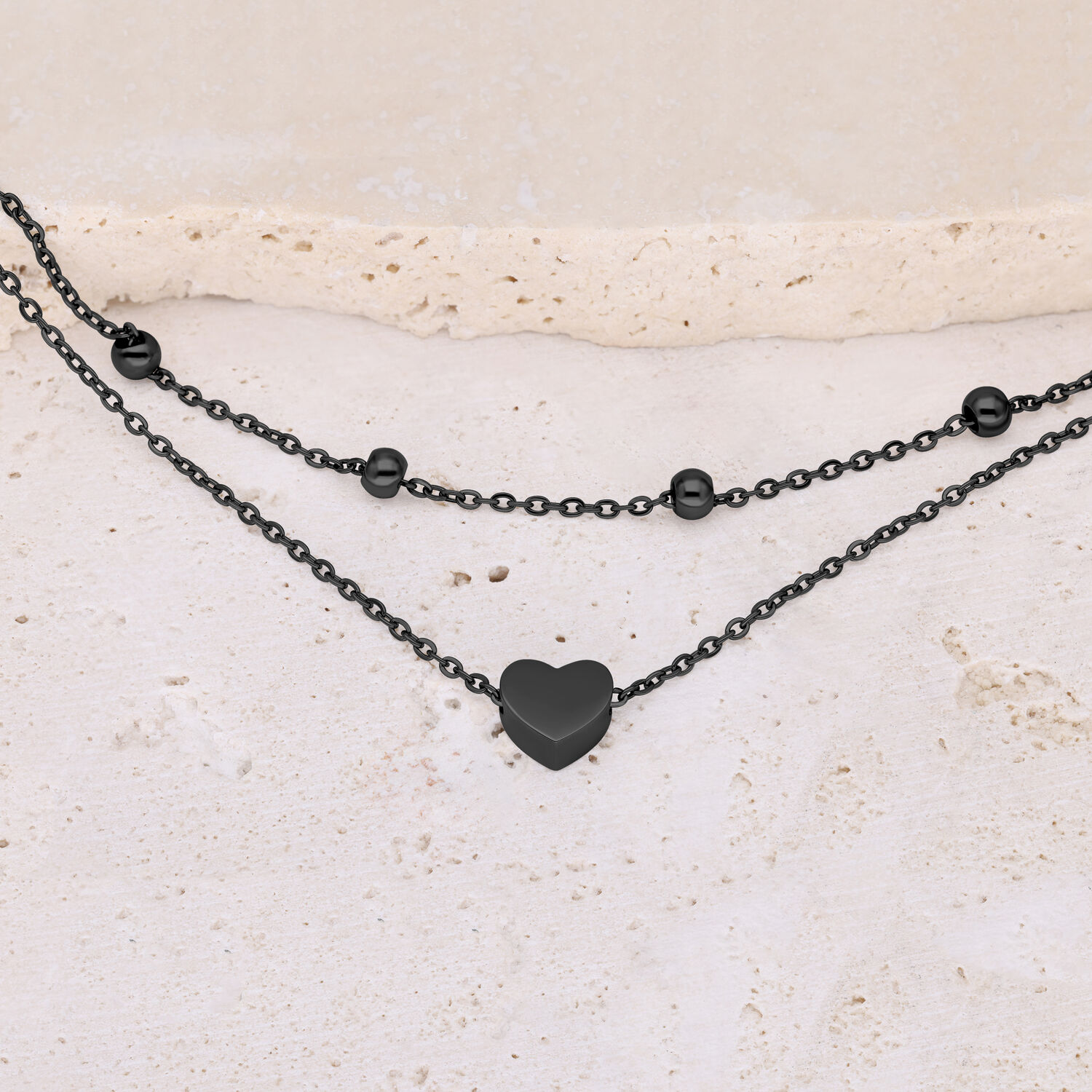 Bracciale nero con ciondolo a cuore su pietra chiara