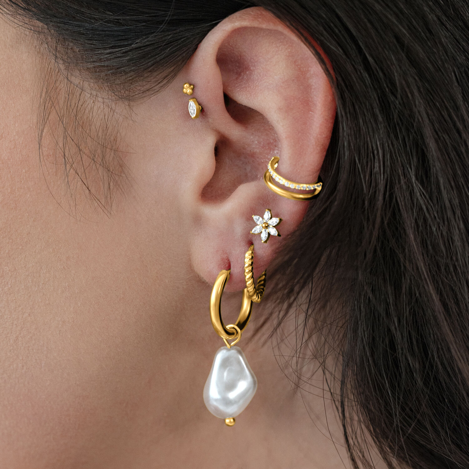 Barocke Perlen Creolen aus goldenem Metall Goldene Creolen mit barocker Perle am Ohr einer Person, auf neutralem Hintergrund