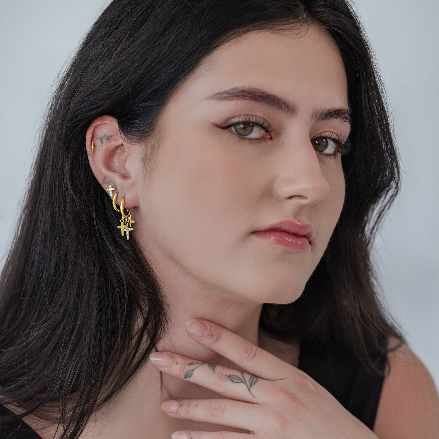 Frau mit goldenen Kreuz Creolen, glänzend, auf neutralem Hintergrund