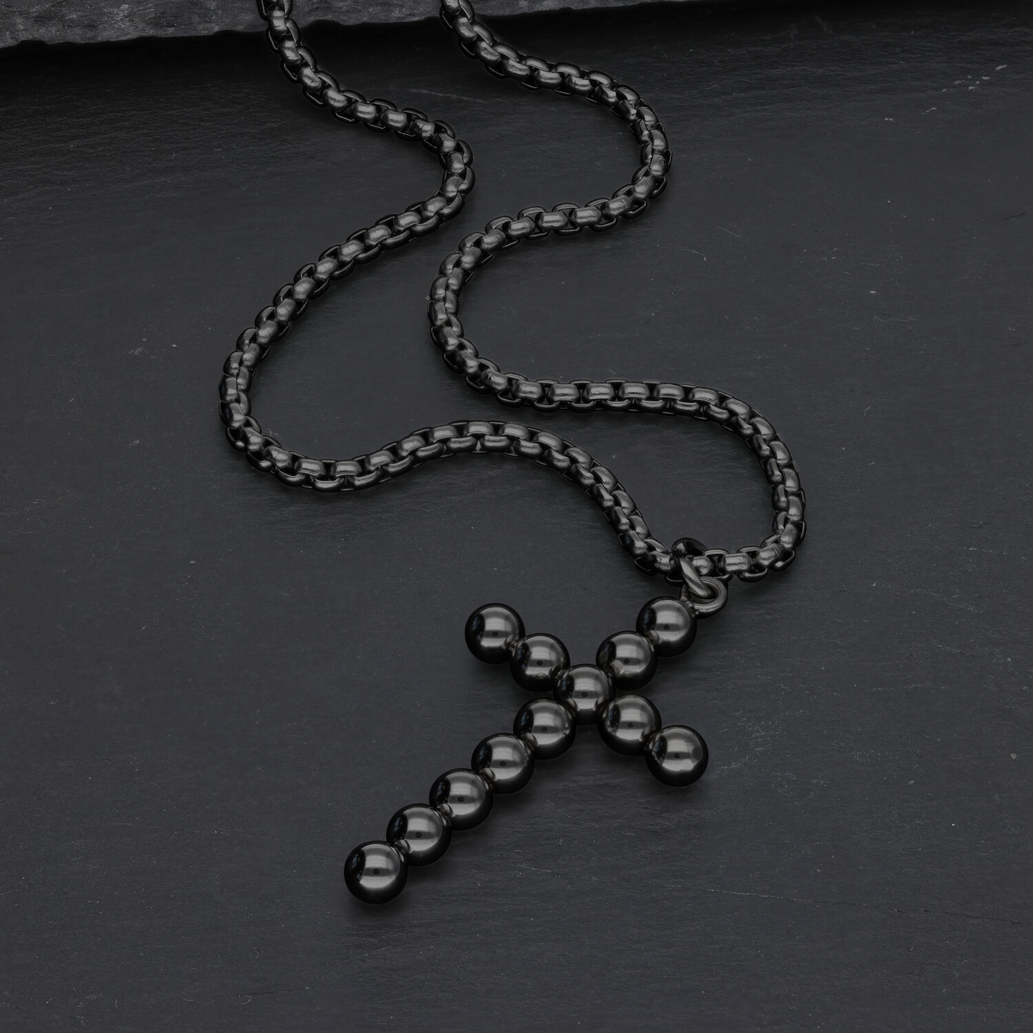 Collana nera con ciondolo a croce di sfere su sfondo scuro