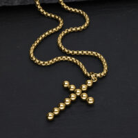 Goldene Bubble Kreuzkette aus Chirurgenstahl Goldene Kreuzkette aus Kugeln auf schwarzem Hintergrund