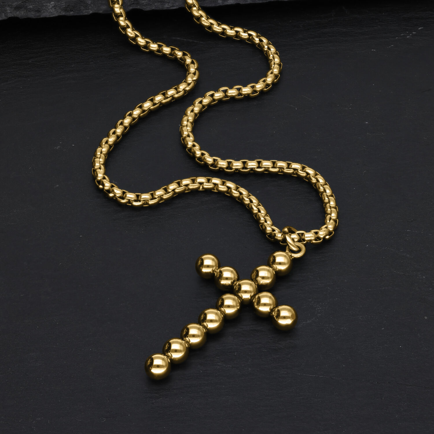 Goldene Bubble Kreuzkette aus Chirurgenstahl Goldene Kreuzkette aus Kugeln auf schwarzem Hintergrund