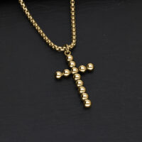Bubble Cross Kette aus Gold Goldene Bubble Cross Halskette aus Chirurgenstahl auf schwarzem Hintergrund