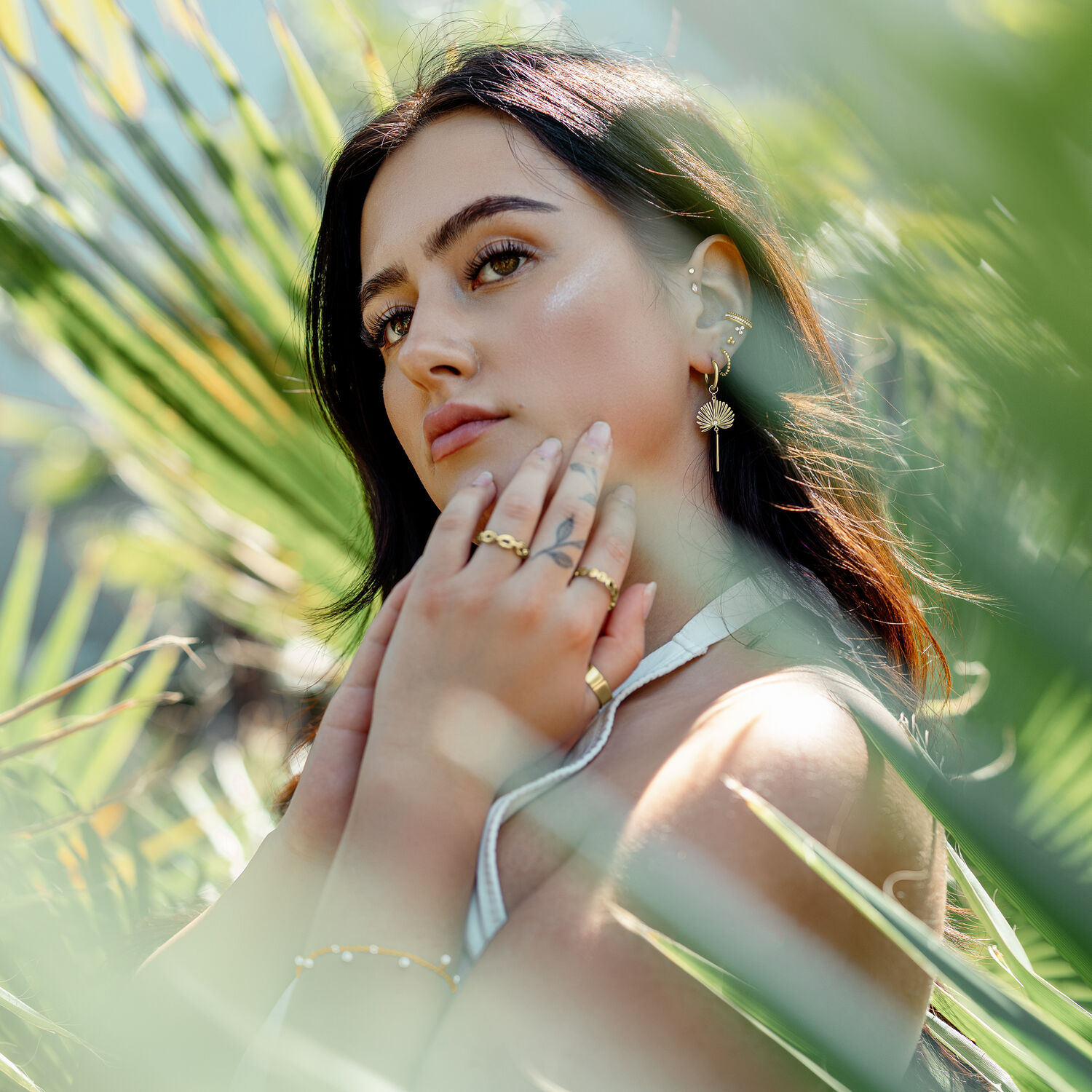 Junge Frau trägt goldene Little Petticoat Hoops, umgeben von grünen Blättern