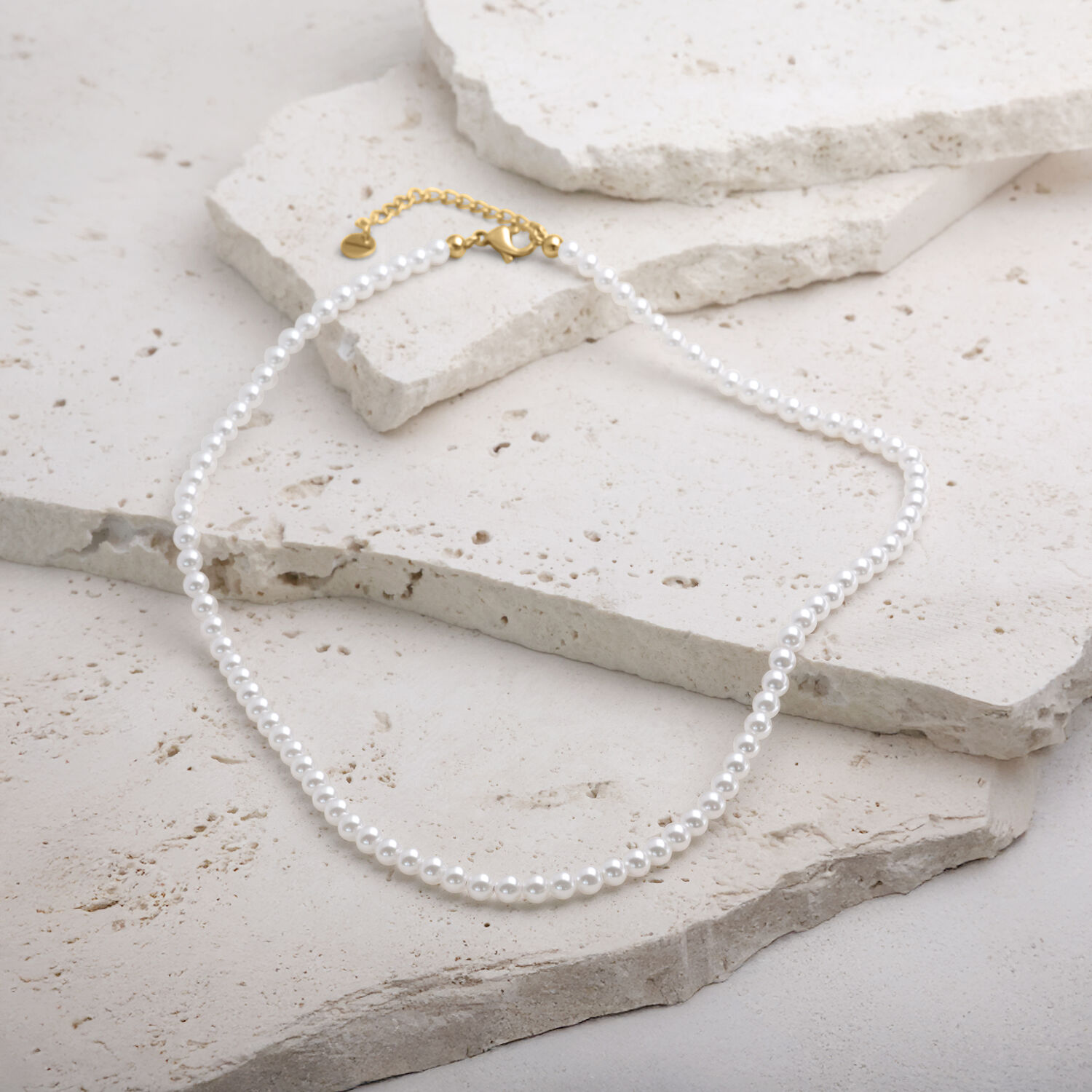 Kleine synthetische Perlenkette mit goldfarbenem Metallverschluss auf hellem Hintergrund