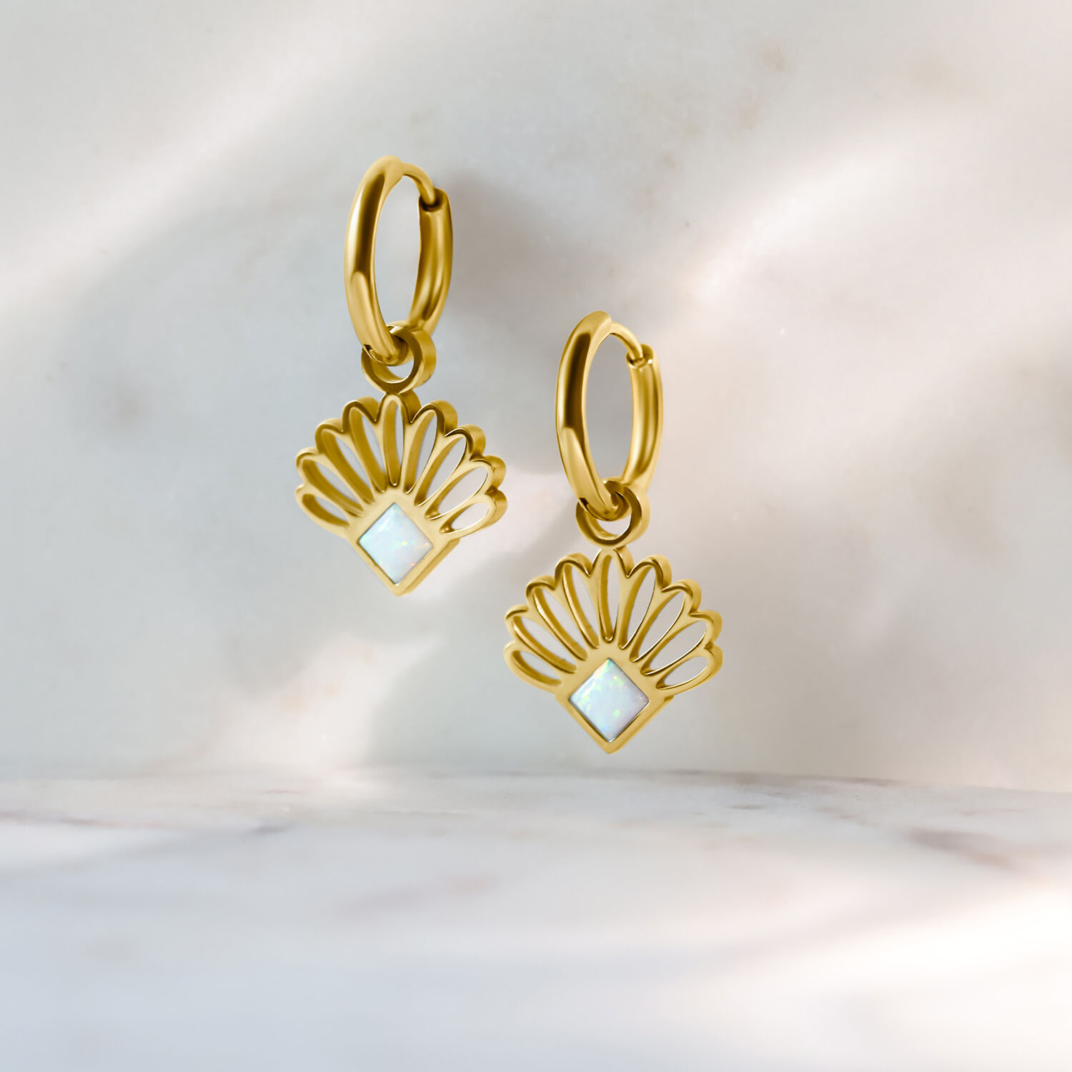 Zwei goldene Creolen mit opalartigem Lüfterdesign auf hellem Hintergrund