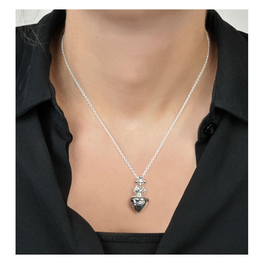 Collana argento con pendente a croce e cuore su sfondo neutro