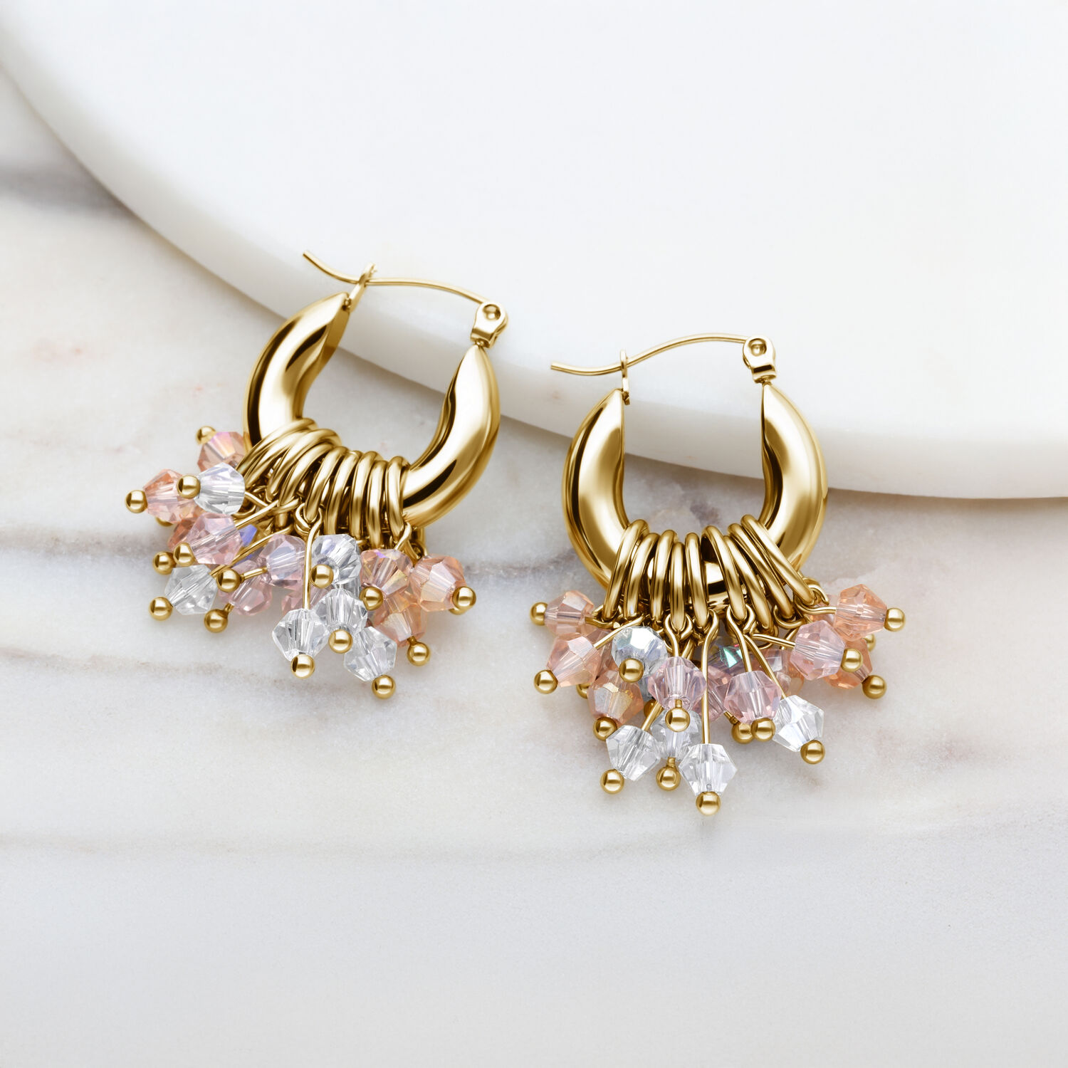 Goldene Creolen-Ohrringe mit bunten Kristallanhängern auf weißem Hintergrund