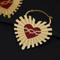 Goldene Creolen in Herzform mit Dornenmotiv auf schwarzem Hintergrund