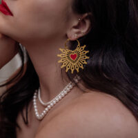 Goldene Creolen Ohrringe mit rotem Herz auf einer Frau