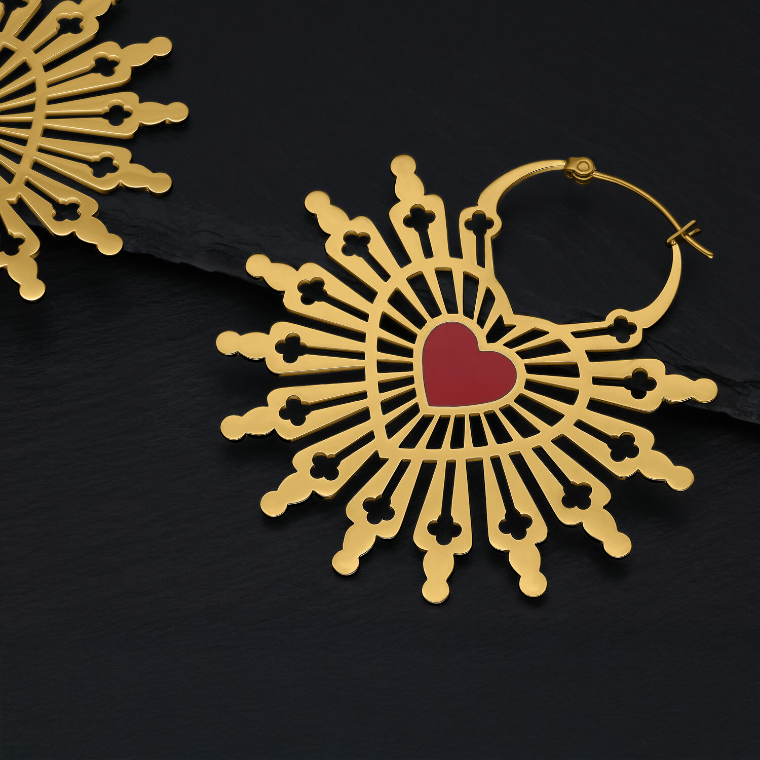 Goldene Ohrringe in Herzform auf schwarzem Hintergrund