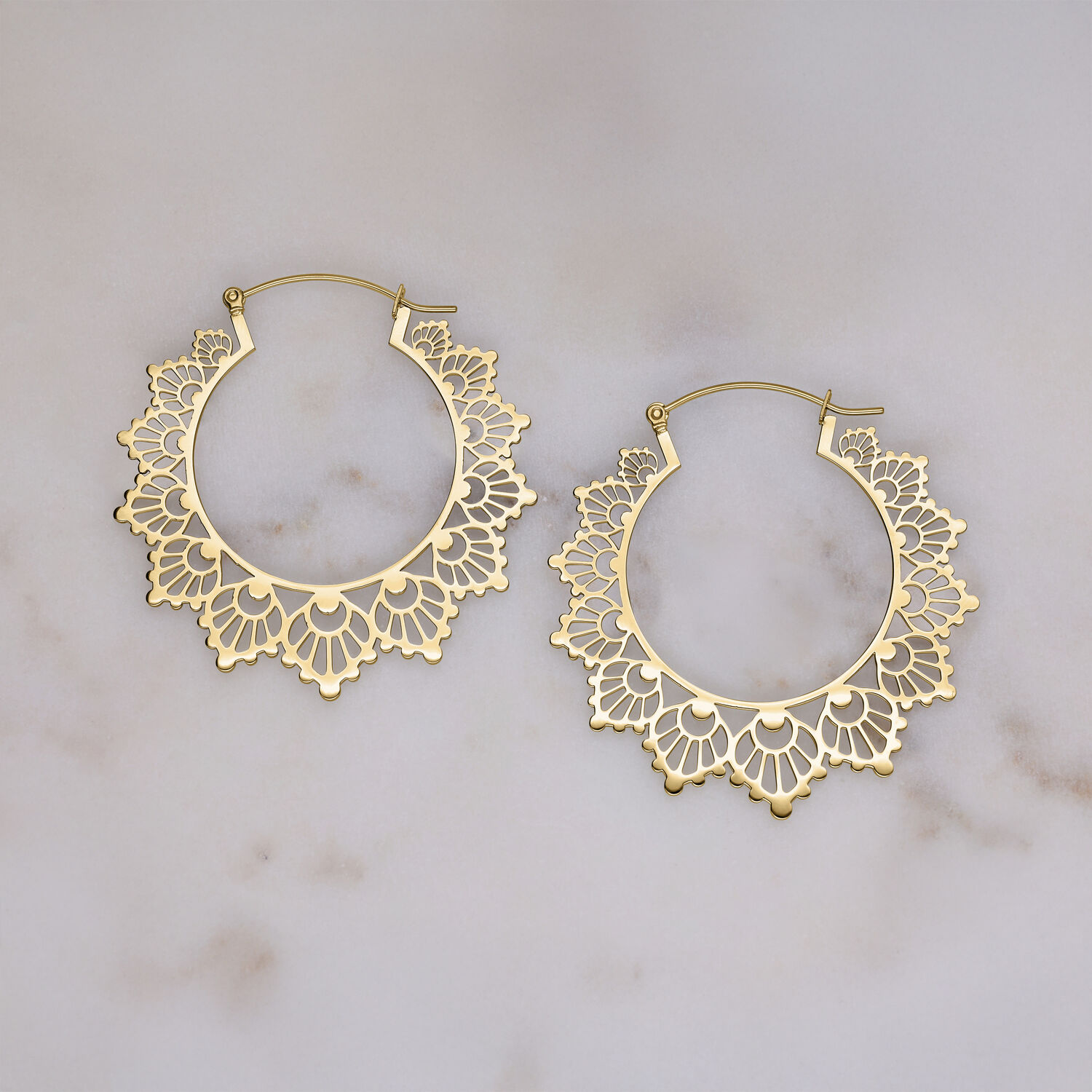 Goldene Creolen in Sonnenblumen-Design auf hellem Hintergrund