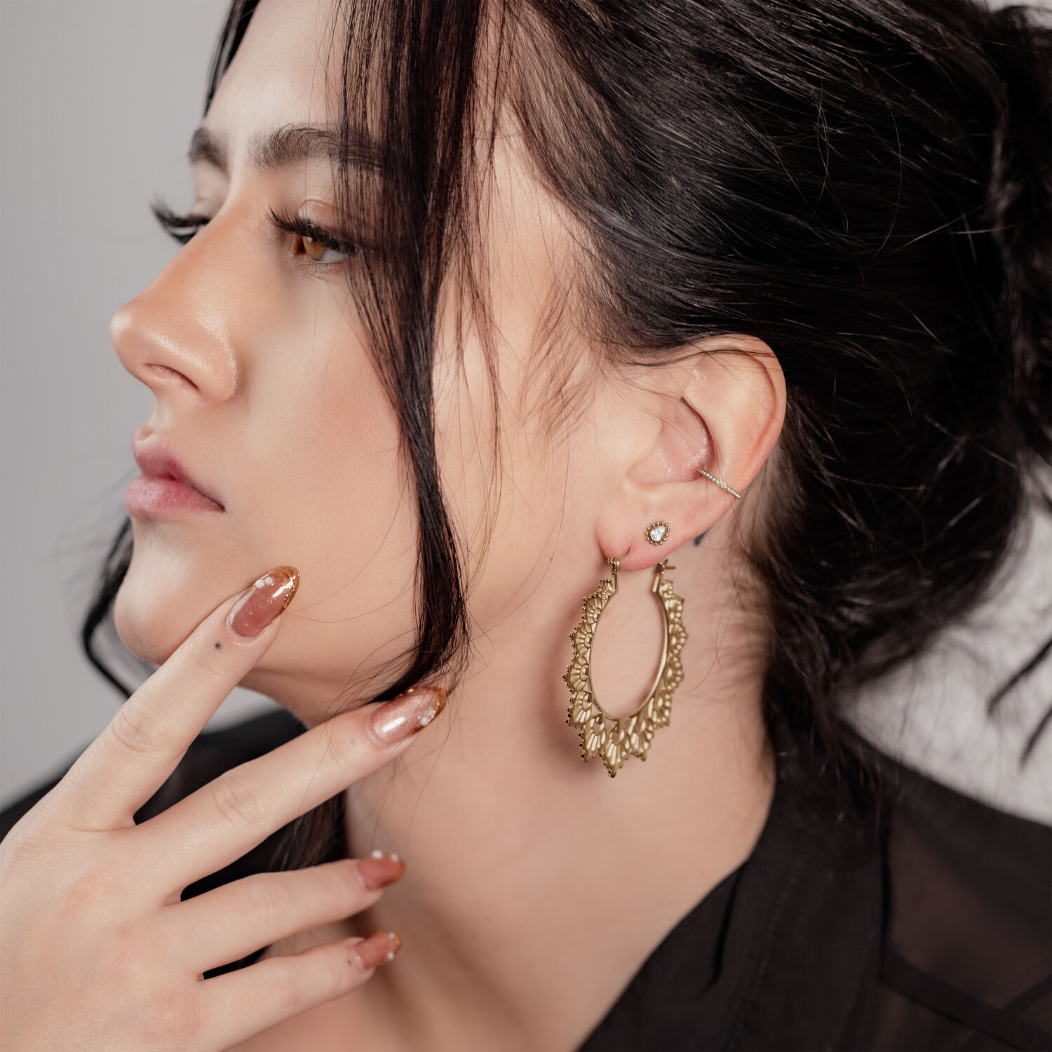 Frau mit goldenen Sonnenblumen-Ohrringen, seitliches Profil, schwarzes Haar