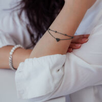 Bracciale cuore nero a doppia fila su braccio di una persona con camicia bianca