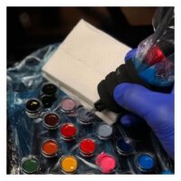 Asciugamani da tatuaggio bianchi accanto a colori per tatuaggi e guanti