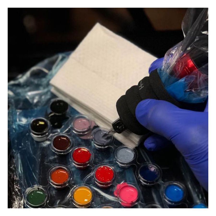 Asciugamani da tatuaggio bianchi accanto a colori per tatuaggi e guanti